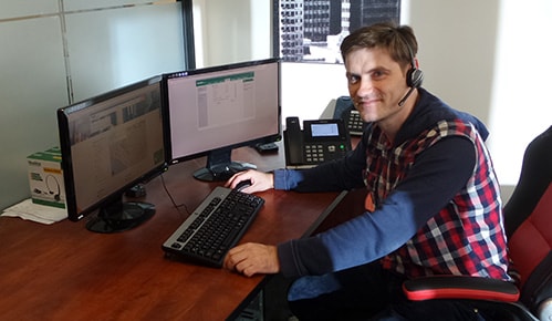 guy smiling and sitting next to computer